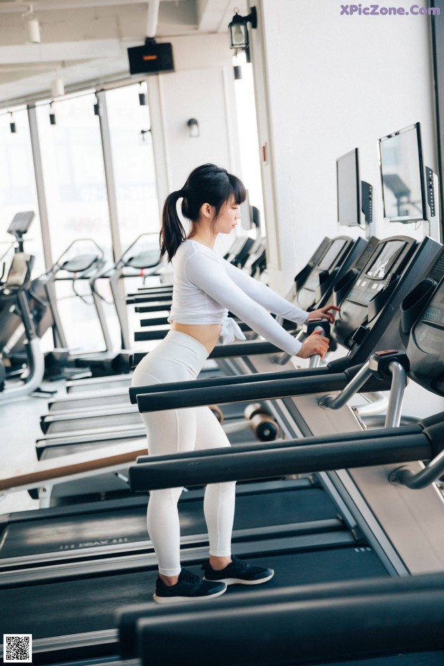 A woman running on a treadmill in a gym.