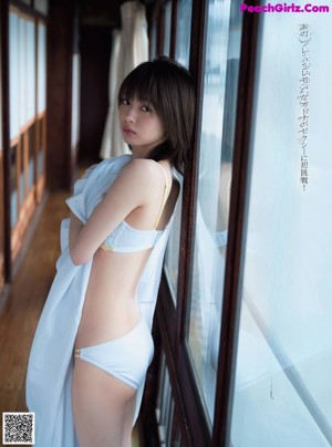 A woman laying on top of a bed next to a window.