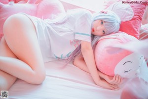 A woman laying on a bed with pink stuffed animals.