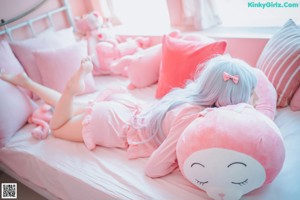 A woman laying on a bed with pink stuffed animals.