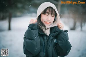 A woman in a black coat is standing in the snow.