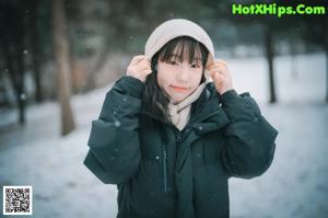 A woman standing in the snow wearing a scarf.