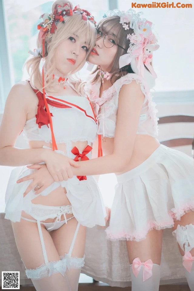 Two young women dressed in white and pink are posing for a picture.