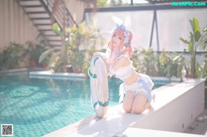 A woman in a bunny costume posing by a pool.