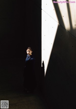 A woman standing in front of a wall in a dark room.