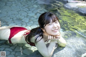 A woman in a red bikini sitting on a rock.