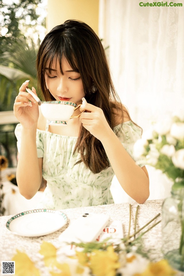 A woman sitting at a table with a cup of tea.