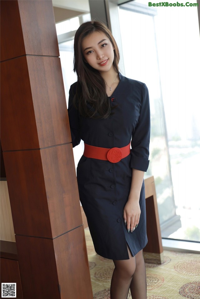 A woman in a black dress with a red belt.
