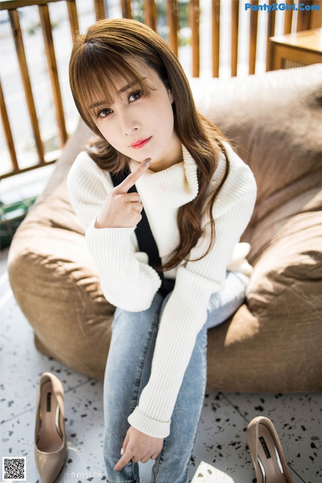A woman sitting on a couch with her finger on her lips.