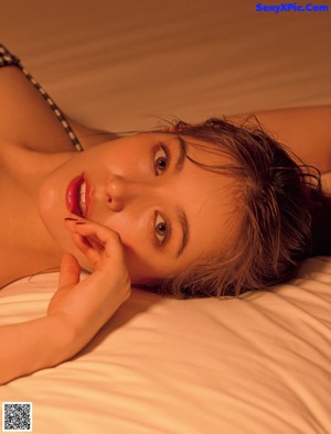 A woman laying on top of a bed in a black and white checkered underwear.