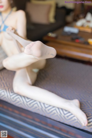 A woman in a blue bikini sitting on a couch.