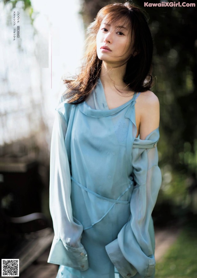 A woman in a blue dress standing in a park.