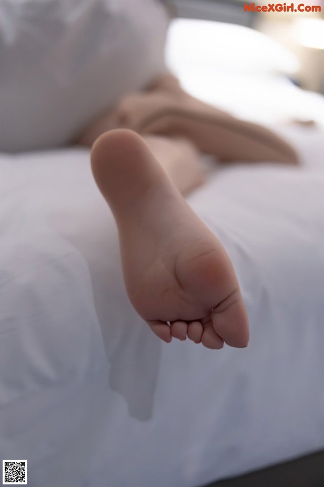 A person laying on a bed with their feet up.