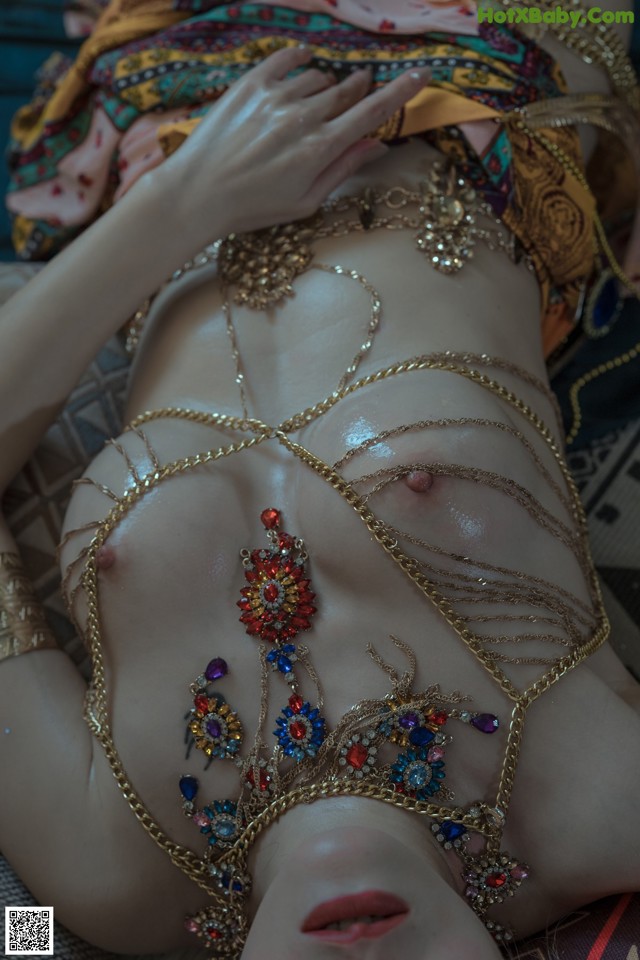 A woman laying on top of a bed covered in jewelry.