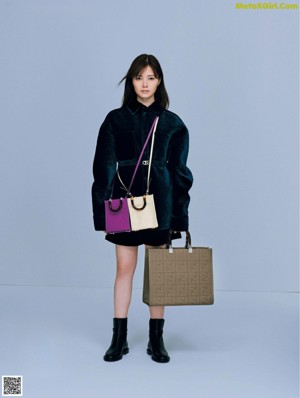 A woman in a brown sweater holding a red bag.