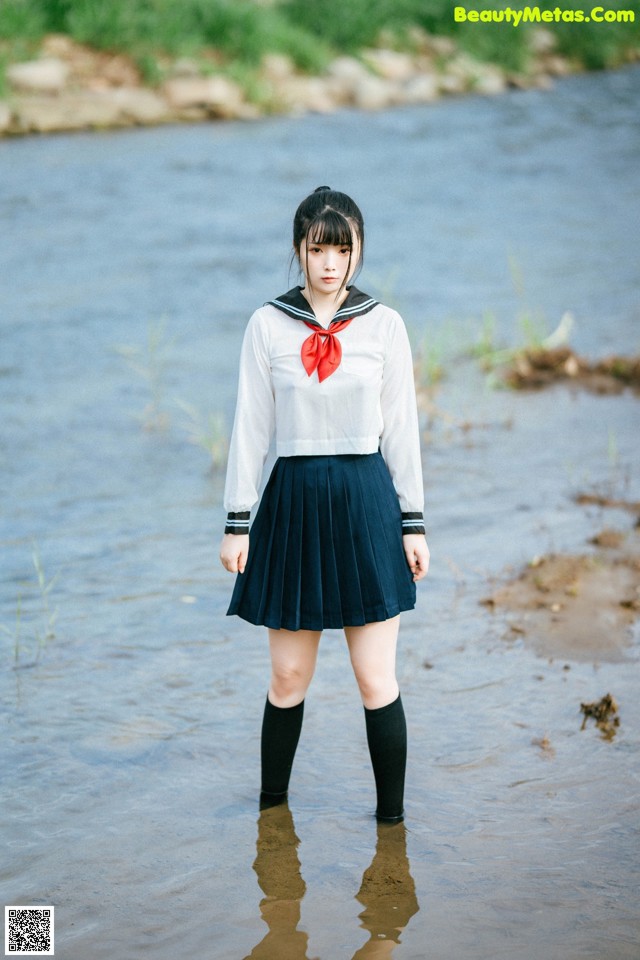 A woman in a school uniform standing in the water.