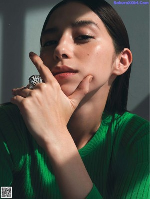 A woman wearing a black turtle neck sweater and a green ring.