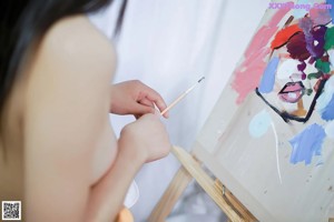 A woman in a white shirt is sitting on a chair.