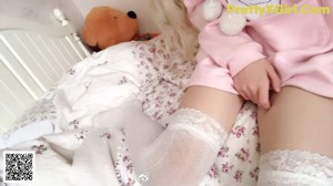 A woman in a nurse outfit laying on a bed with a teddy bear.