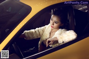 A woman posing in front of a yellow sports car.