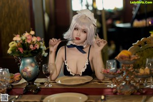 A woman in a maid outfit sitting at a table.