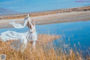 A woman in a white dress is standing in the water.