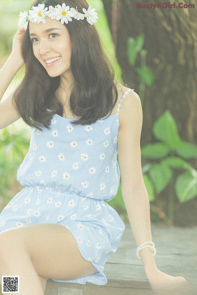 A woman in a blue dress sitting on a wooden bench.