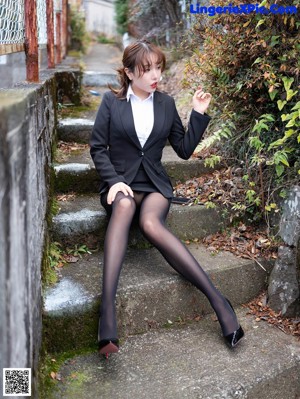 A woman in a black fishnet bodysuit and bunny ears sitting on the floor.