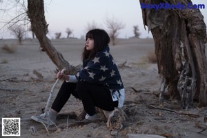 A little girl sitting on a wooden bench in a park.