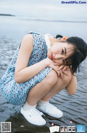 A woman in a blue dress standing by the water.