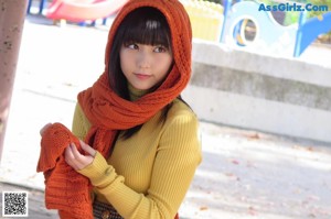A woman leaning against a pole in a park.