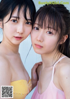 A couple of women standing on top of a pier next to the ocean.