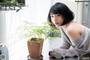 A woman sitting on top of a kitchen counter next to a sink.