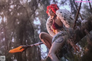 A woman with red hair sitting on a tree branch.