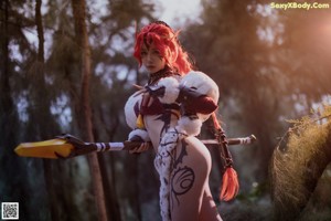 A woman with red hair sitting in the grass holding a sword.