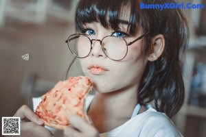 A woman in a white shirt and pink panties holding a donut.