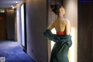 A woman in a green dress sitting on a bathroom counter.