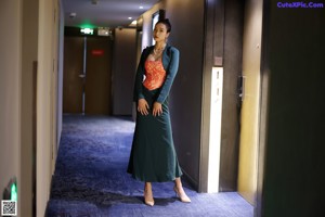 A woman in a green dress standing in a hallway.