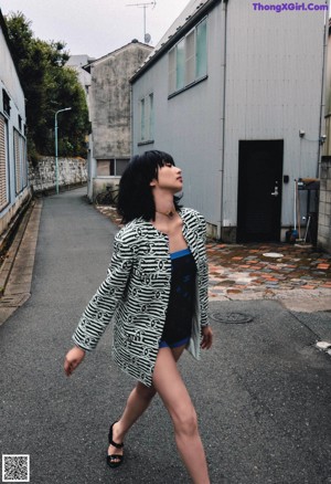A woman in a purple dress leaning against a wall.
