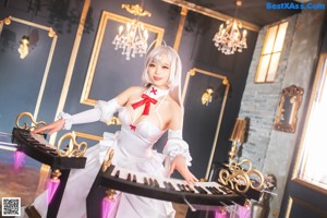 A woman in a white dress sitting on a piano.