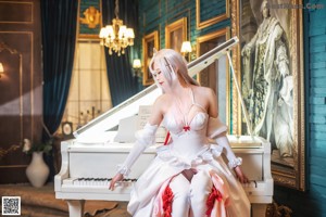 A woman in a white dress sitting at a piano.